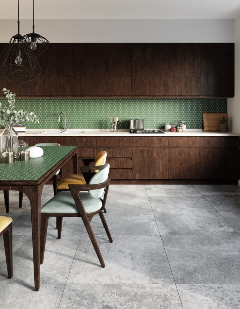 Cuisine moderne bois foncé, crédence carreaux hexagonaux verts. Table à manger verte, chaises bicolores. Suspensions géométriques noires, sol béton.