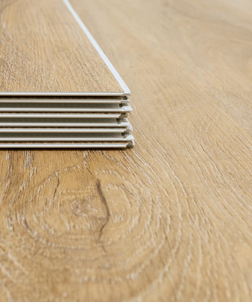 Pile de lames de revêtement de sol en bois clair texturé, prêtes à être installées sur un plancher assorti.
